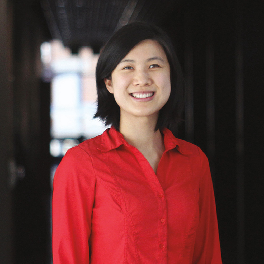 A headshot photograph of Julianna Gesun smiling while standing in a hallway