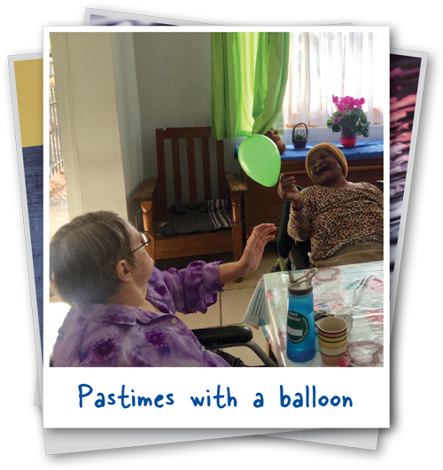 2 elderly women playing with green balloon on polaroid
